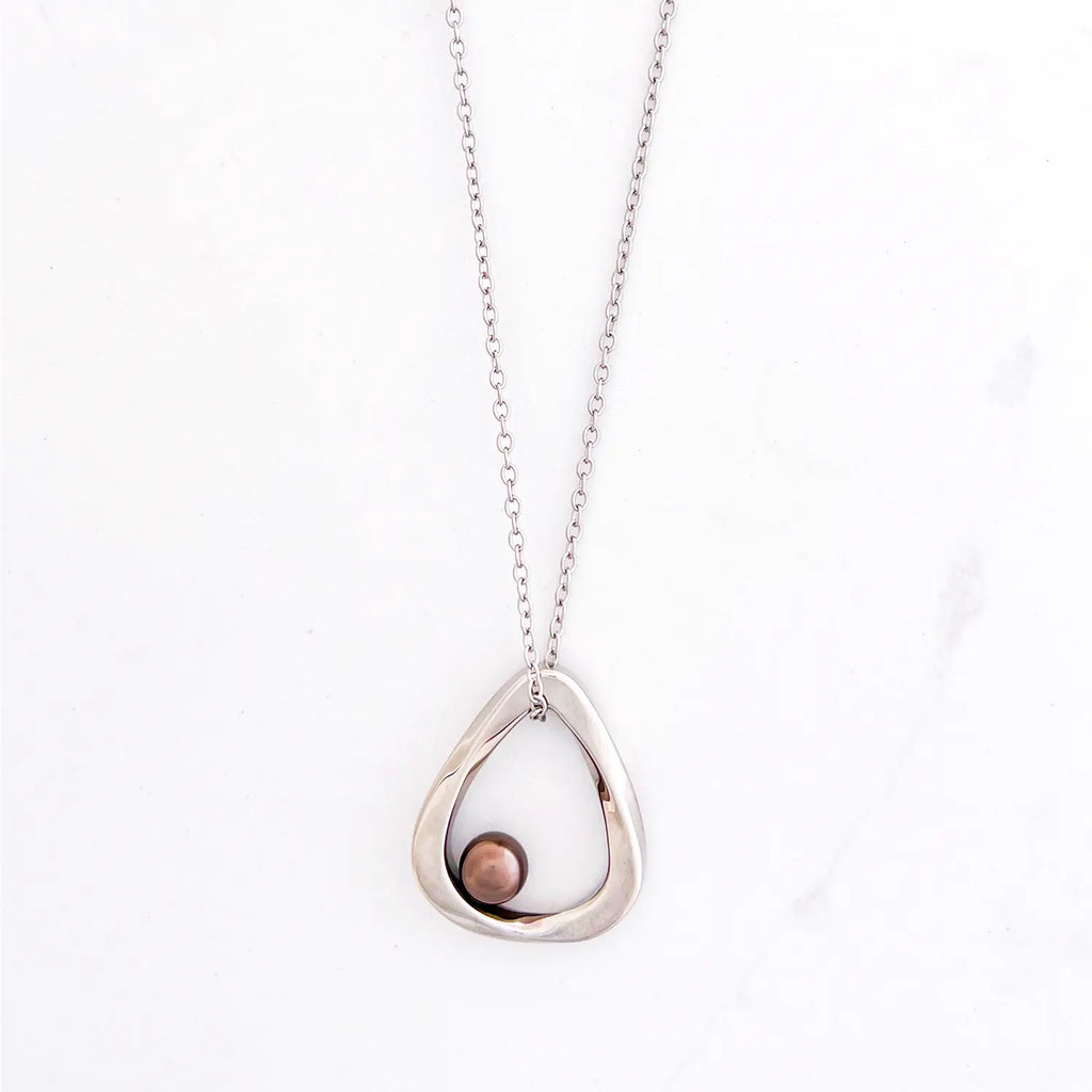 Silver color stainless steel chain with cutout, open center pendant and small copper ball at bottom of center.