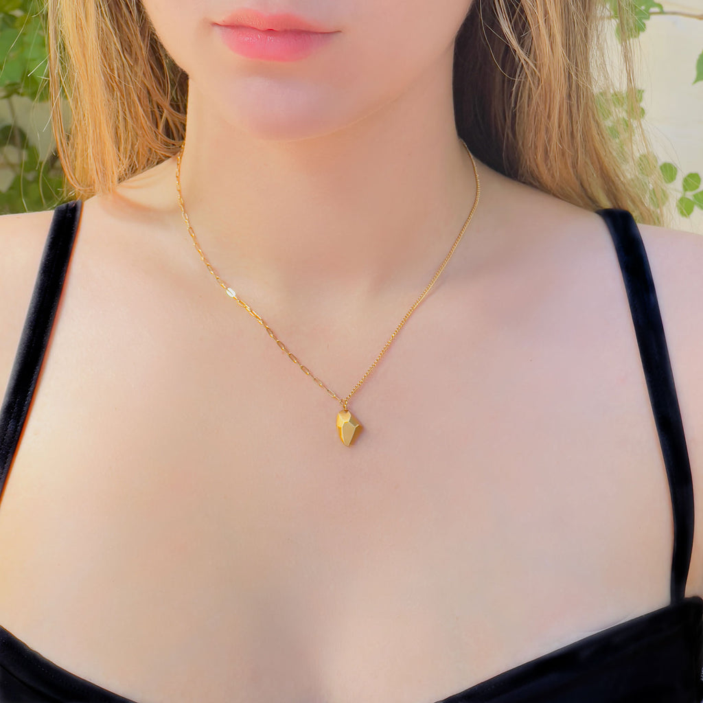Girl wearing 18k gold plated stainless steel cable and curb split chain with small geometric gold-plated rock style pendant. One half of chain is a wider open chain (while still being dainty), the other half is a more thin compact chain. 