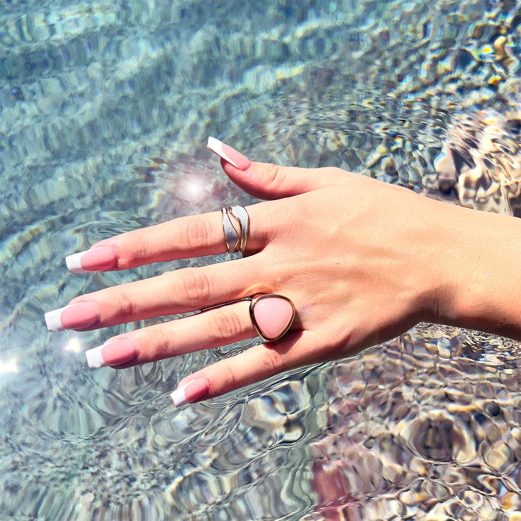 hand over pool wearing 18k gold plated enamel ring. Adjustable ring with wavy structure, color light blue.