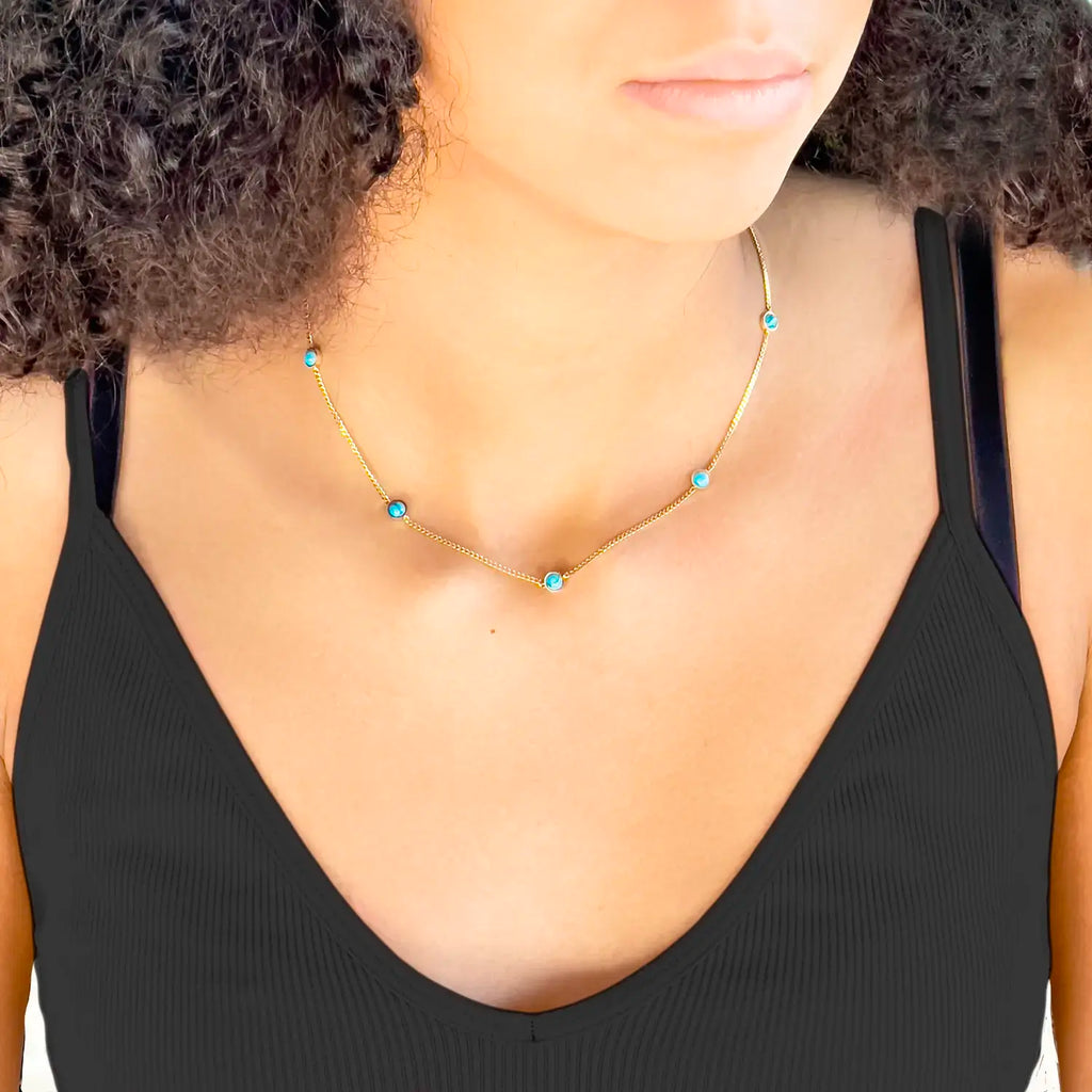 Girl wearing 18k thin gold chain with natural turquoise stone beads spaced evenly along the chain.