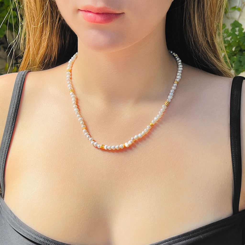 Girl wearing Freshwater pearl beaded necklace with 18k gold plated beads spaced out a few times along the necklace.