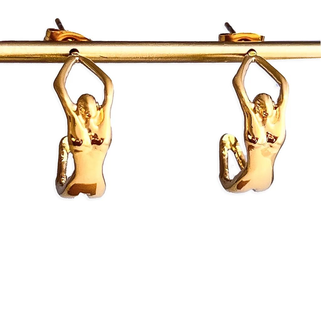 18k gold small hoop earrings shaped as person/girl arched back into a half-circle. shown hanging from a gold bar earring holder.