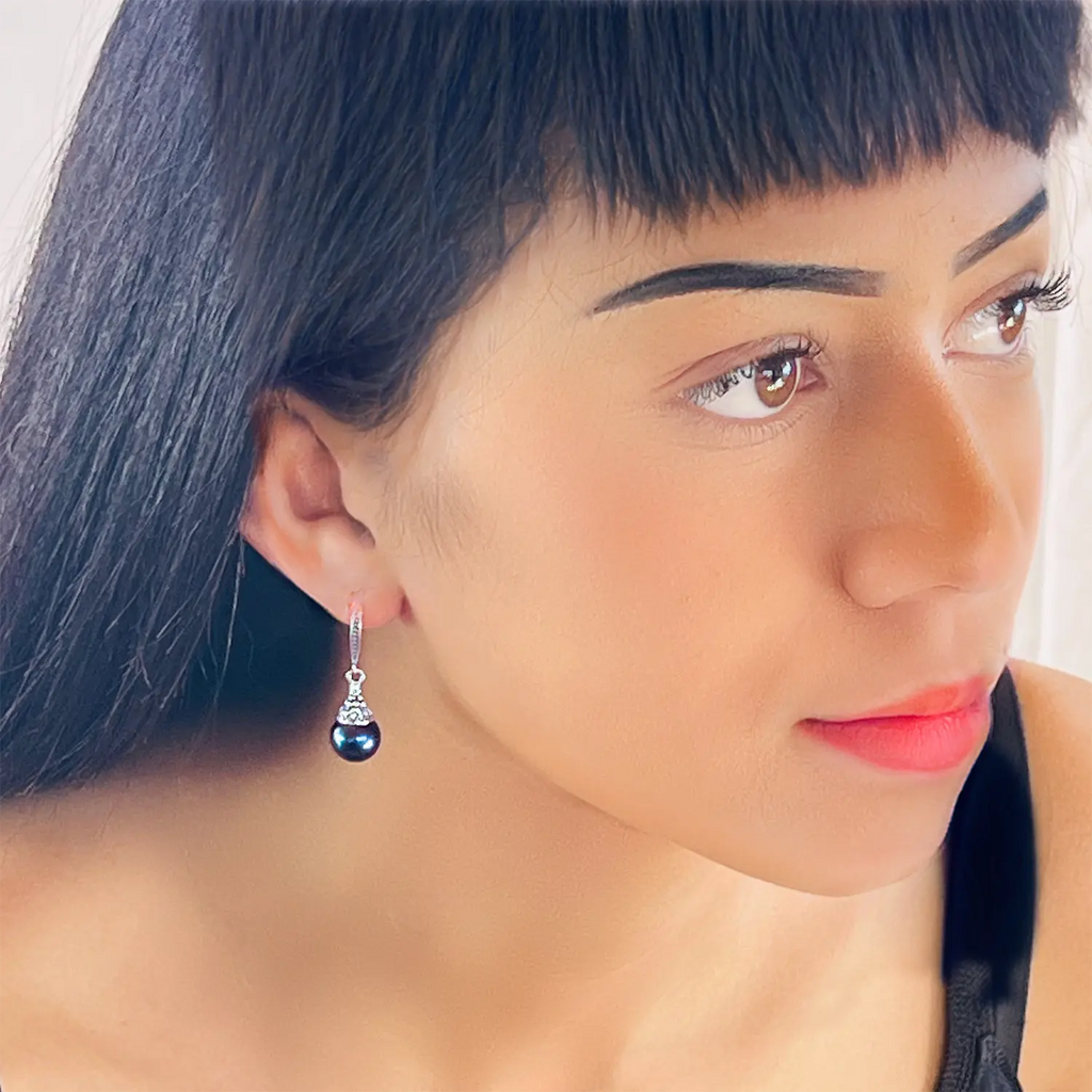 Girl wearing black freshwater pearl and sterling silver drop earrings with a fishhook backing. Sterling silver has a pattern engraved. 