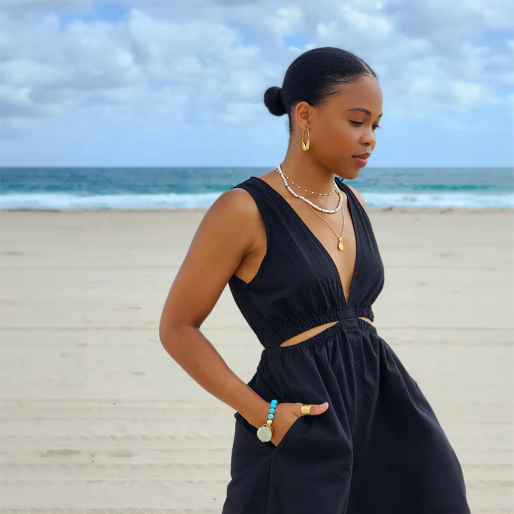 Girl at beach wearing 18k gold plated "hammered" adjustable ring, wide and plate with indented pattern.