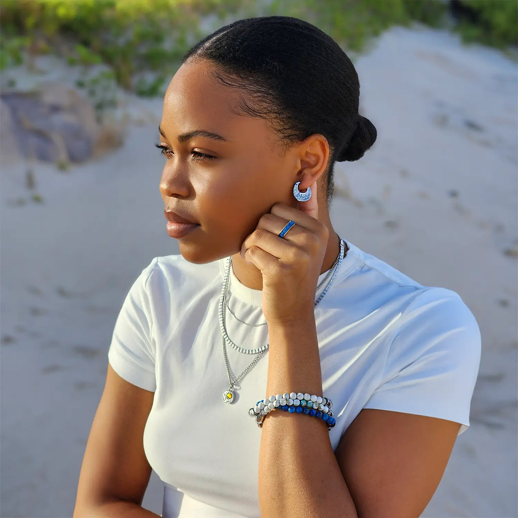 Girl at the beach wearing Silver flower engraved small hoop earrings. Paired with 3 layered silver chain and pendent necklaces.