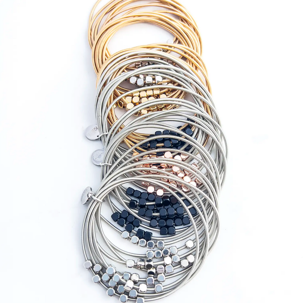 Stainless steel silver and gold-plated stacked 8-wire guitar string bracelets with colored loose beads all styles stacked together.