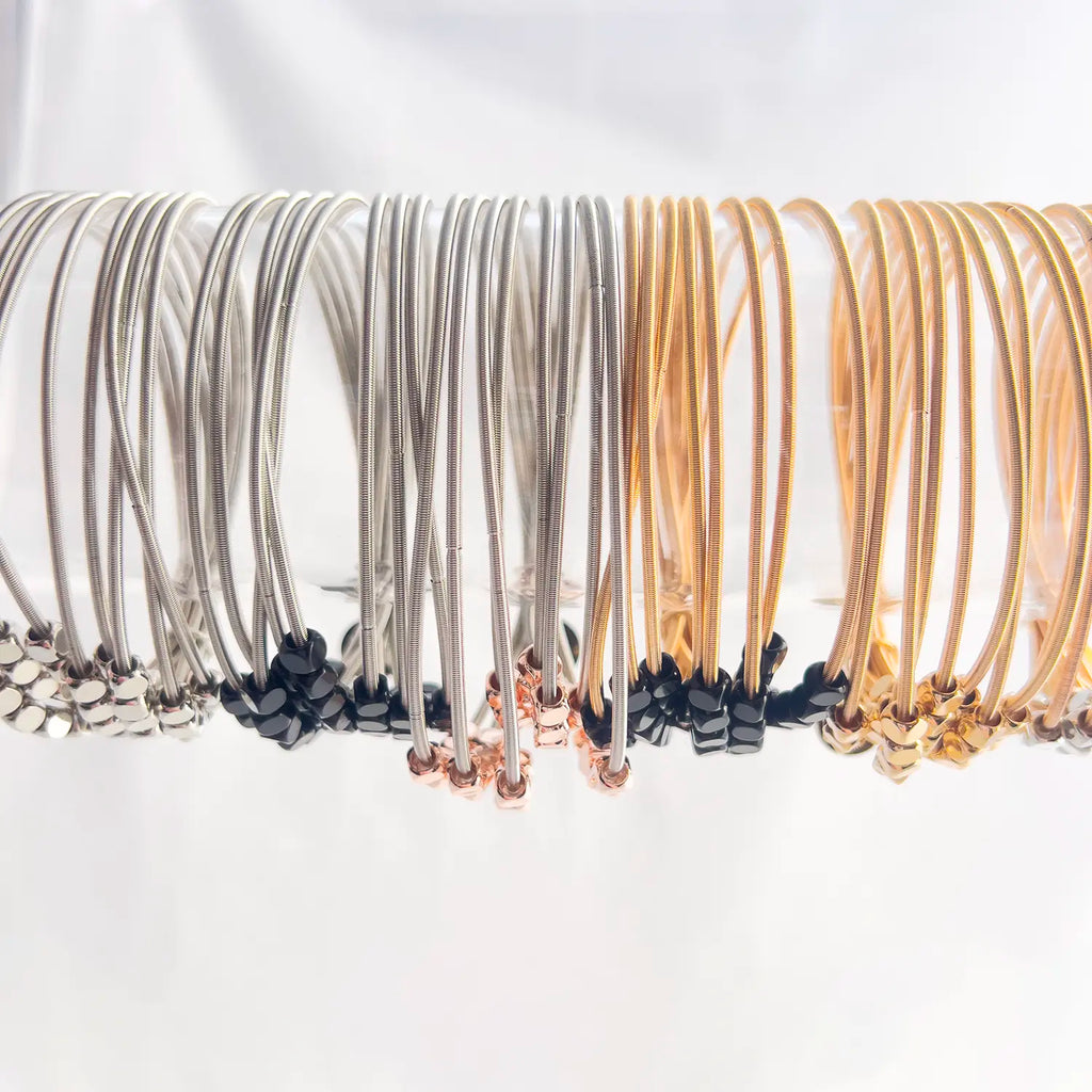 Stainless steel silver and gold-plated stacked 8-wire guitar string bracelets with colored loose beads all styles stacked together.