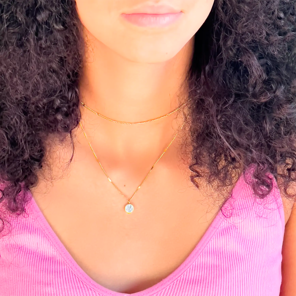 Girl wearing 18k gold plated double layer chain necklace and circle shell pendant.