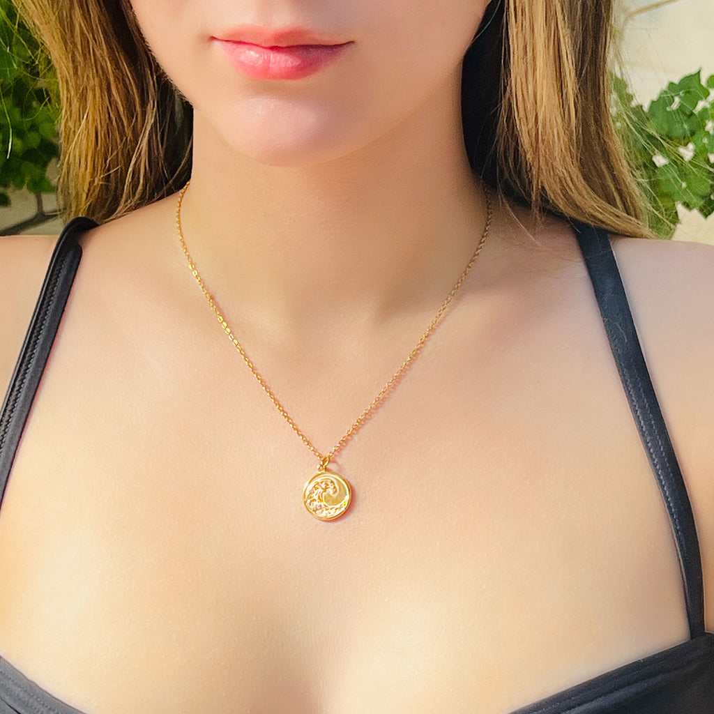 girl wearing 18k gold plated pendant necklace, pendant is circular with a bubble wave engraving.