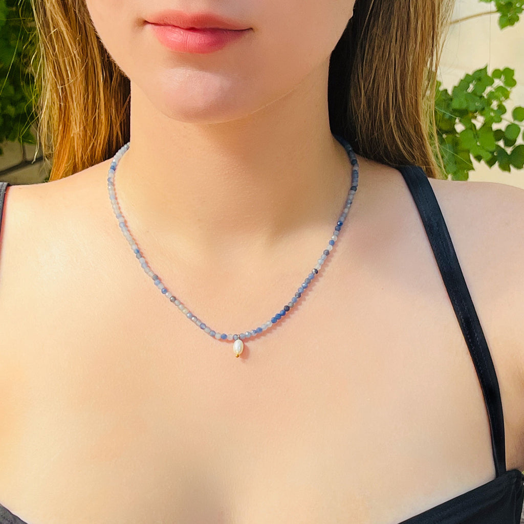 Girl wearing Beaded blue aventurine necklace with different shades of blue and a small freshwater pearl pendant.