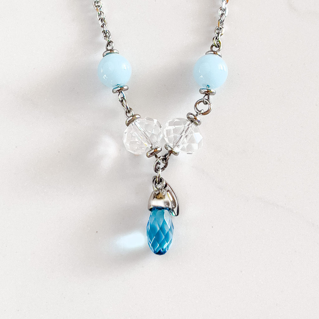 silver stainless steel chain necklace with two light blue beads, two clear stone beads, and an aqua pendant at the bottom.