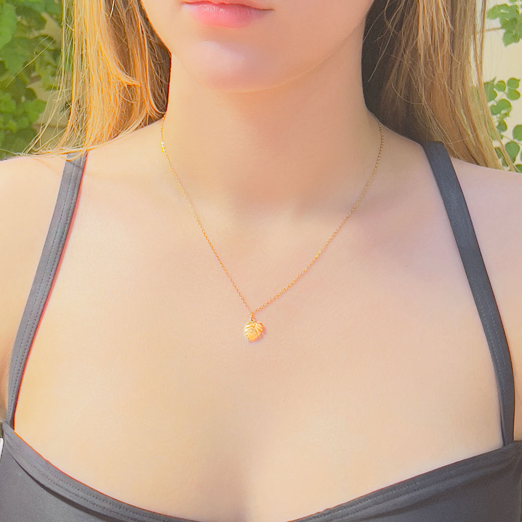 Girl wearing 18k gold plated monstera palm leaf pendant necklace with cable chain.