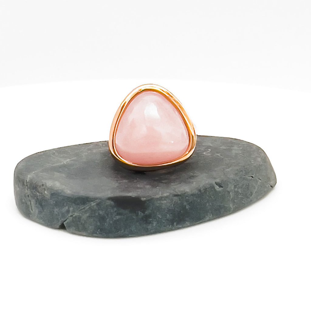 18k gold plated ring with large light pink natural rose quartz stone displayed on a stone