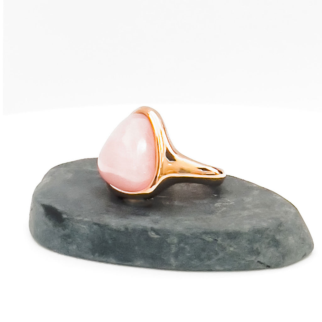 18k gold plated ring with large light pink natural rose quartz stone displayed on a stone.