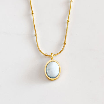18k gold plated pendant necklace. Pendant is a small oval shaped aquamarine cabochon gemstone, with saturn chain.