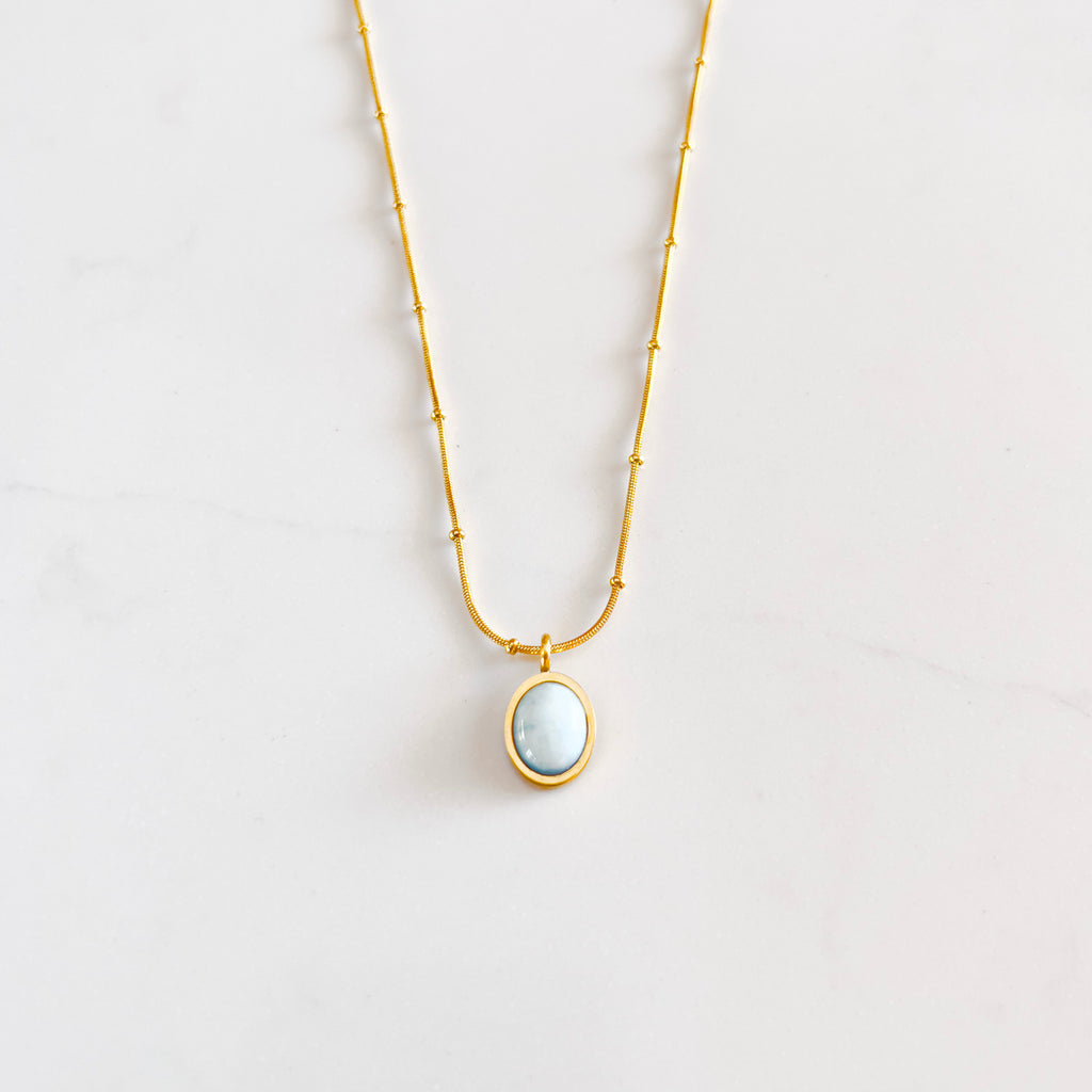 18k gold plated pendant necklace. Pendant is a small oval shaped aquamarine cabochon gemstone, with saturn chain.