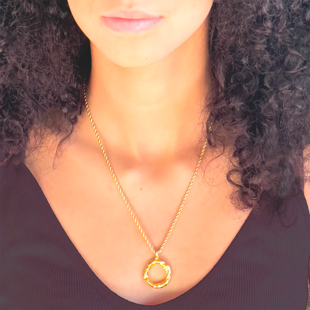 Girl wearing  18k gold plated pendant necklace, pendant is a slightly mishapen circle. (abstract "O" pendant)