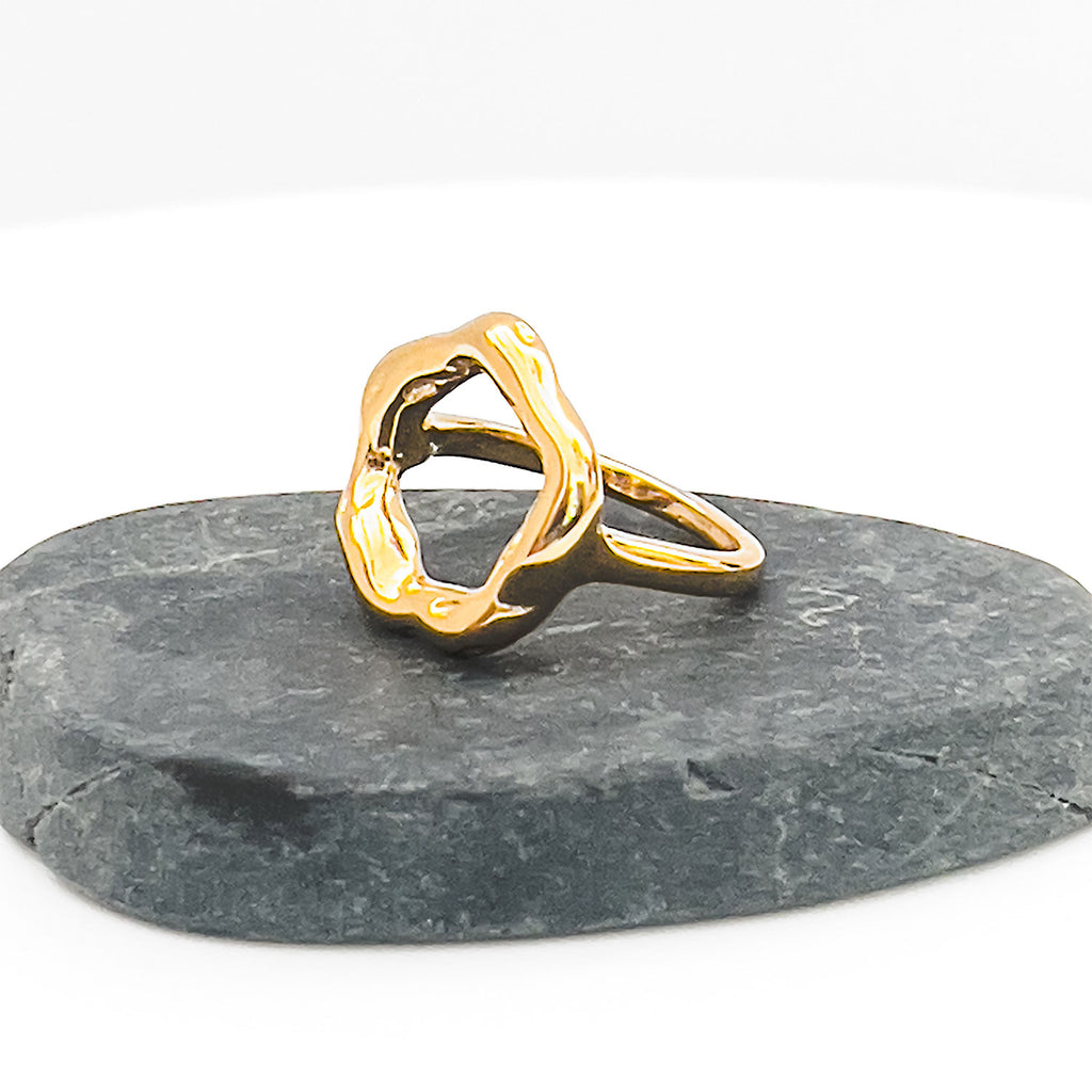 18k gold plated ring with slightly mishapen circle. (abstract "O" on top) and displayed on a stone.
