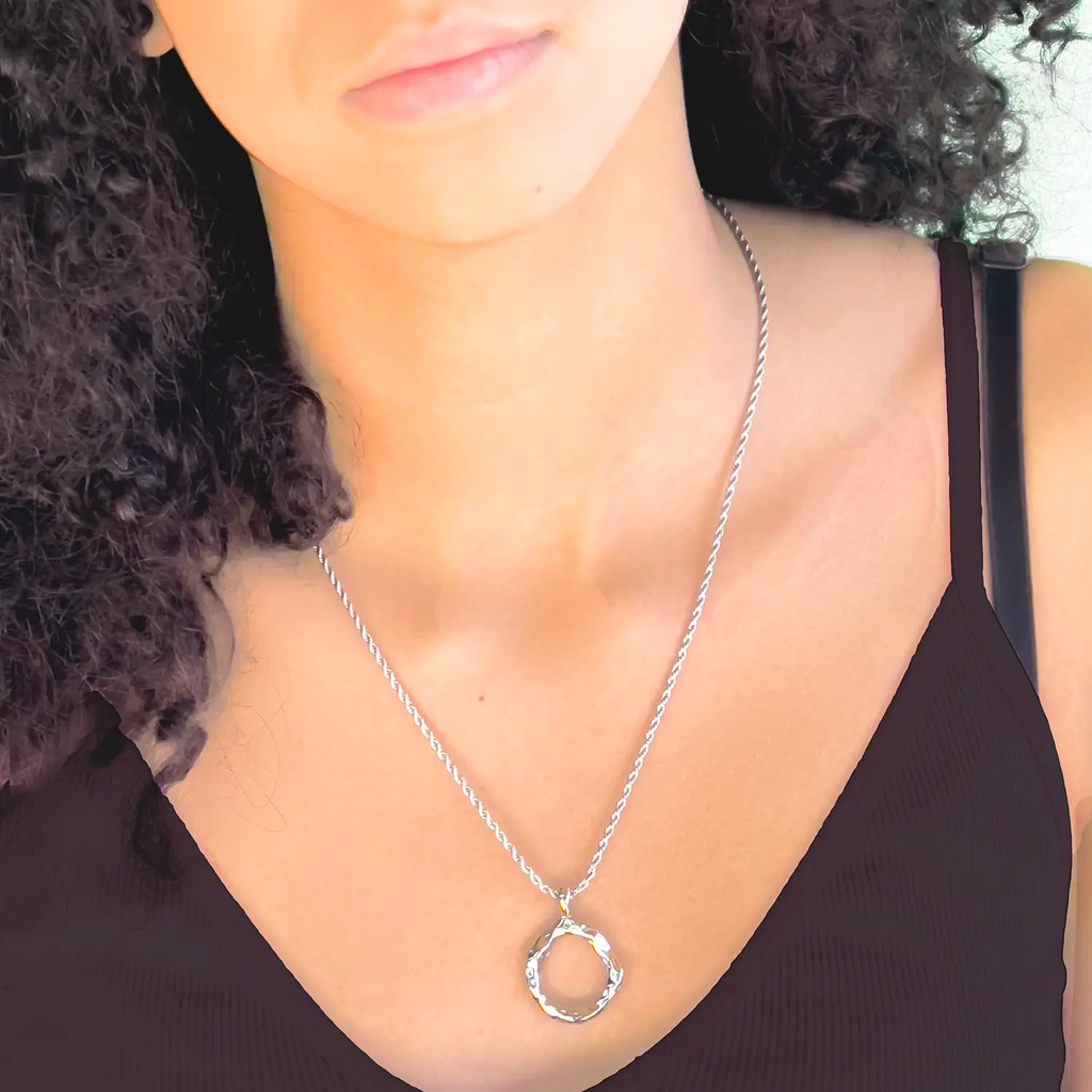 Girl wearing Silver color stainless steel pendant necklace, pendant is a slightly mishapen circle. (abstract "O" pendant)