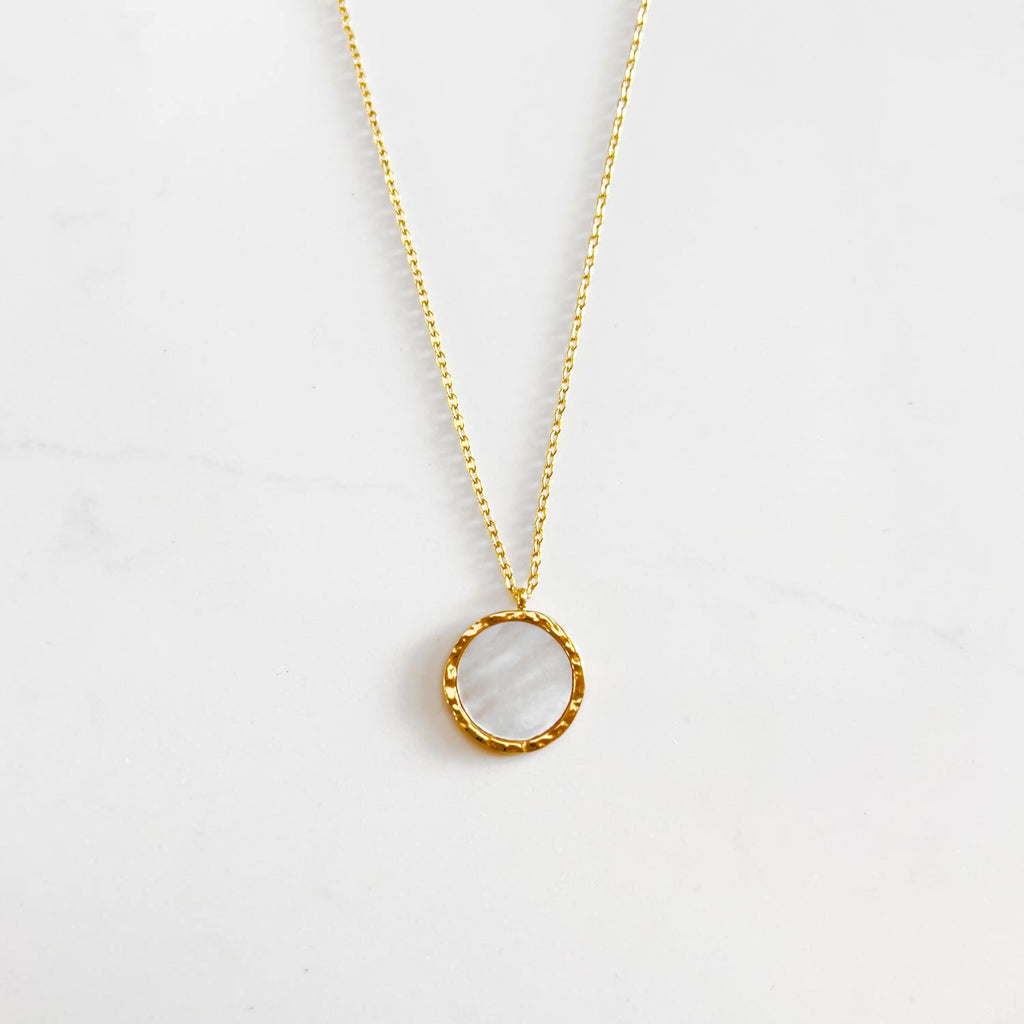 18k gold plated natural shell pendant necklace. pendant is circular with natural shell center and gold plated rimming.