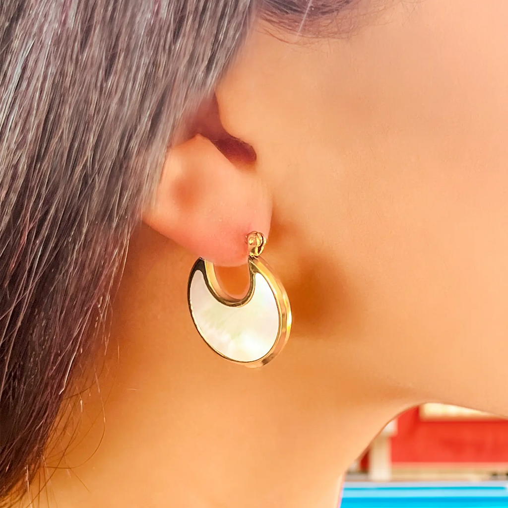 Girl wearing 18k gold plated crescent moon earrings, the inside of the crescent moon is malachite and natural shell, color white with the gold plated rim.