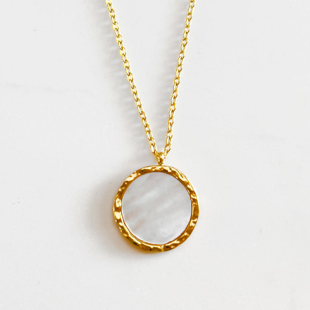 18k gold plated natural shell pendant necklace. pendant is circular with natural shell center and gold plated rimming.